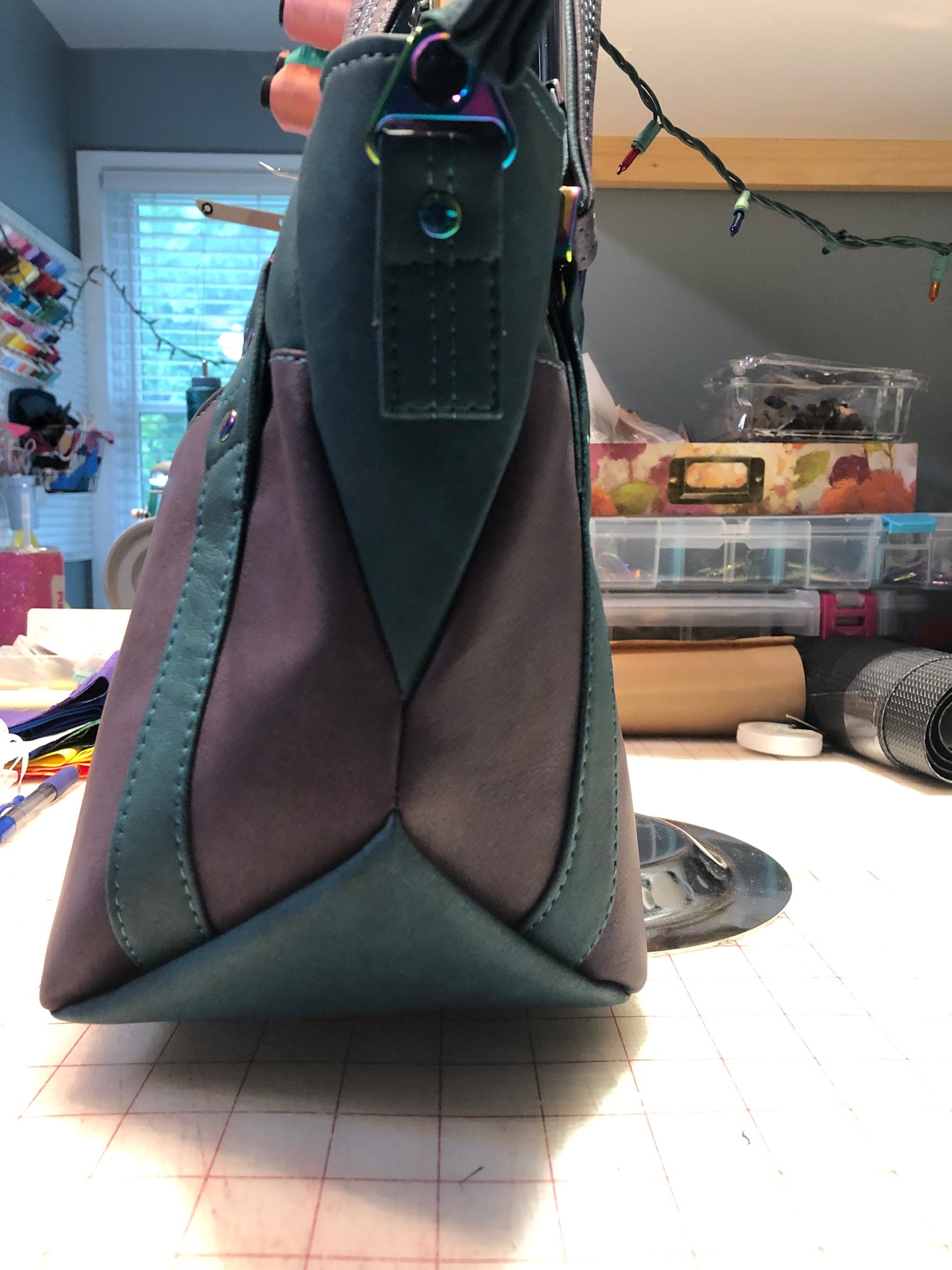 A classy handbag in two beautiful shades of dark teal and purple. There is an adjustable, detachable crossbody strap. Top handles for crook of the arm or shoulder. Exterior has two large slip pockets. Interior has a zipper pocket and two slip pockets. The two colors criss cross at the sides creating a beautiful unique pattern. Pretty lotus flower zipper pulls. At time of this listing, 5 colors available. Message me with any questions. 12” W at the Base, 15” W at the Top, 9 h 6.25 deep