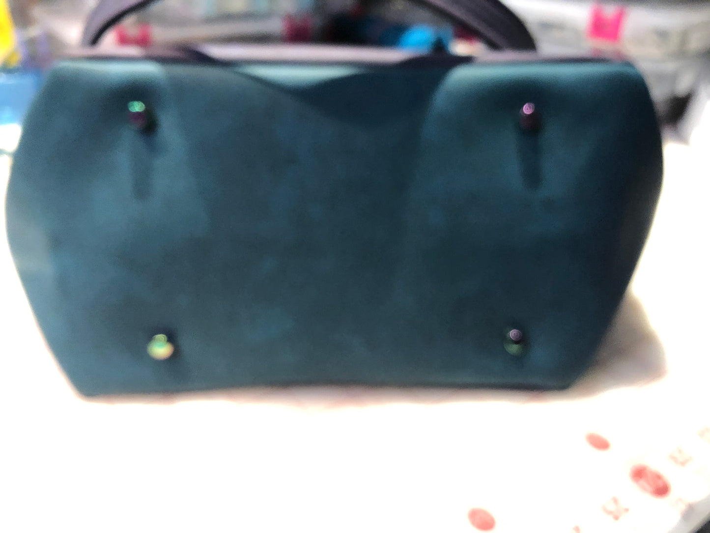A classy handbag in two beautiful shades of dark teal and purple. There is an adjustable, detachable crossbody strap. Top handles for crook of the arm or shoulder. Exterior has two large slip pockets. Interior has a zipper pocket and two slip pockets. The two colors criss cross at the sides creating a beautiful unique pattern. Pretty lotus flower zipper pulls. At time of this listing, 5 colors available. Message me with any questions. 12” W at the Base, 15” W at the Top, 9 h 6.25 deep