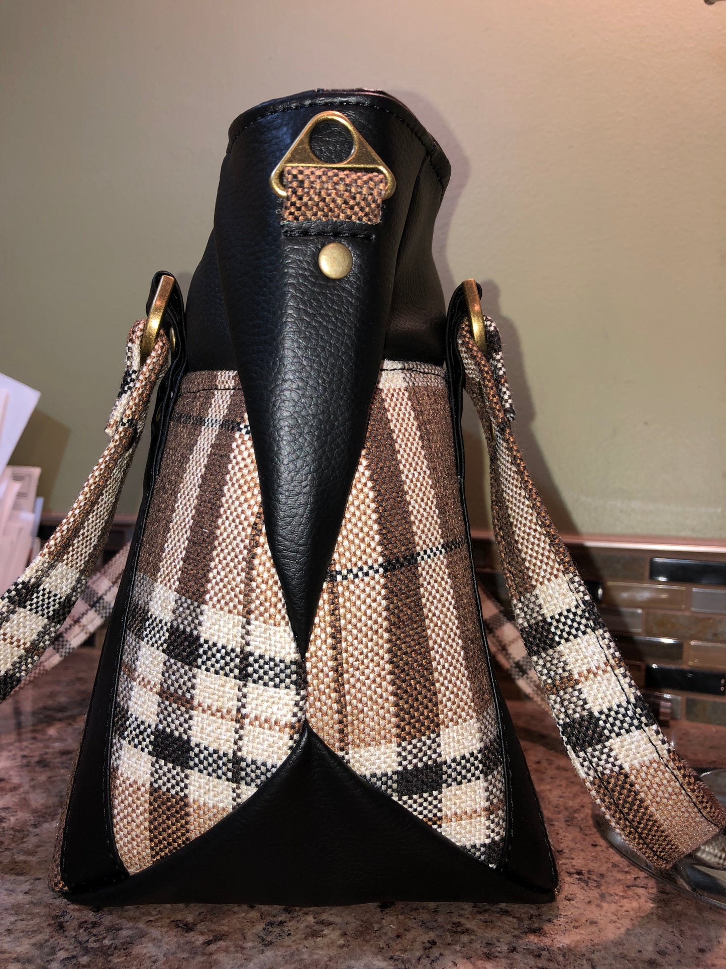 This classy brown and tan paid is a great everyday bag and even better a great bag for the fall season. Both vinyl and woven fabric come together on the sides to make a unique pattern. There is an adjustable, detachable crossbody strap. Top handles for crook of the arm or shoulder.