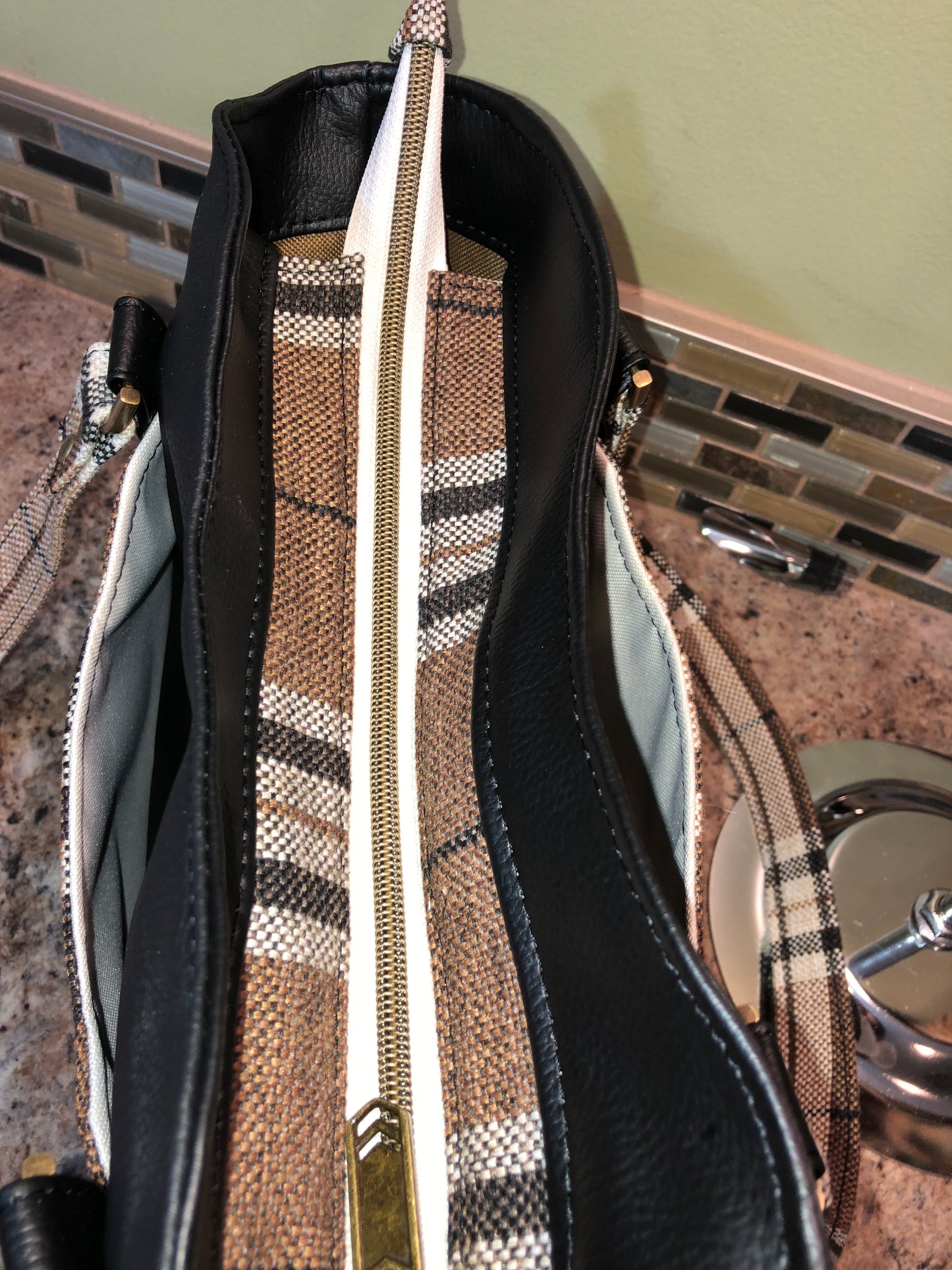 This classy brown and tan paid is a great everyday bag and even better a great bag for the fall season. Both vinyl and woven fabric come together on the sides to make a unique pattern. There is an adjustable, detachable crossbody strap. Top handles for crook of the arm or shoulder.