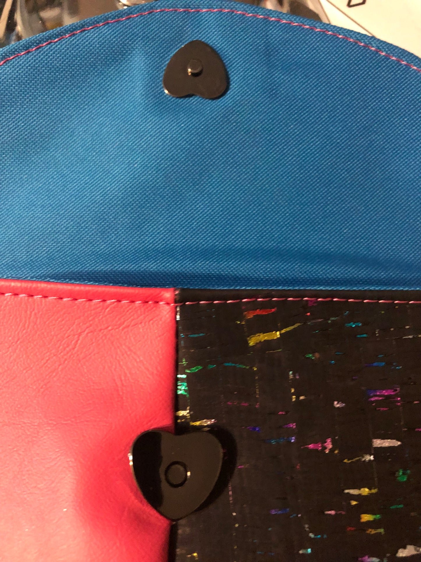 Pretty hot pink clutch with black and rainbow cork. Removable wristlet strap can go on either side of bag. 9" x 6" with four card slots and enough room for a cell phone. Magnetic heart shape snap front closure.