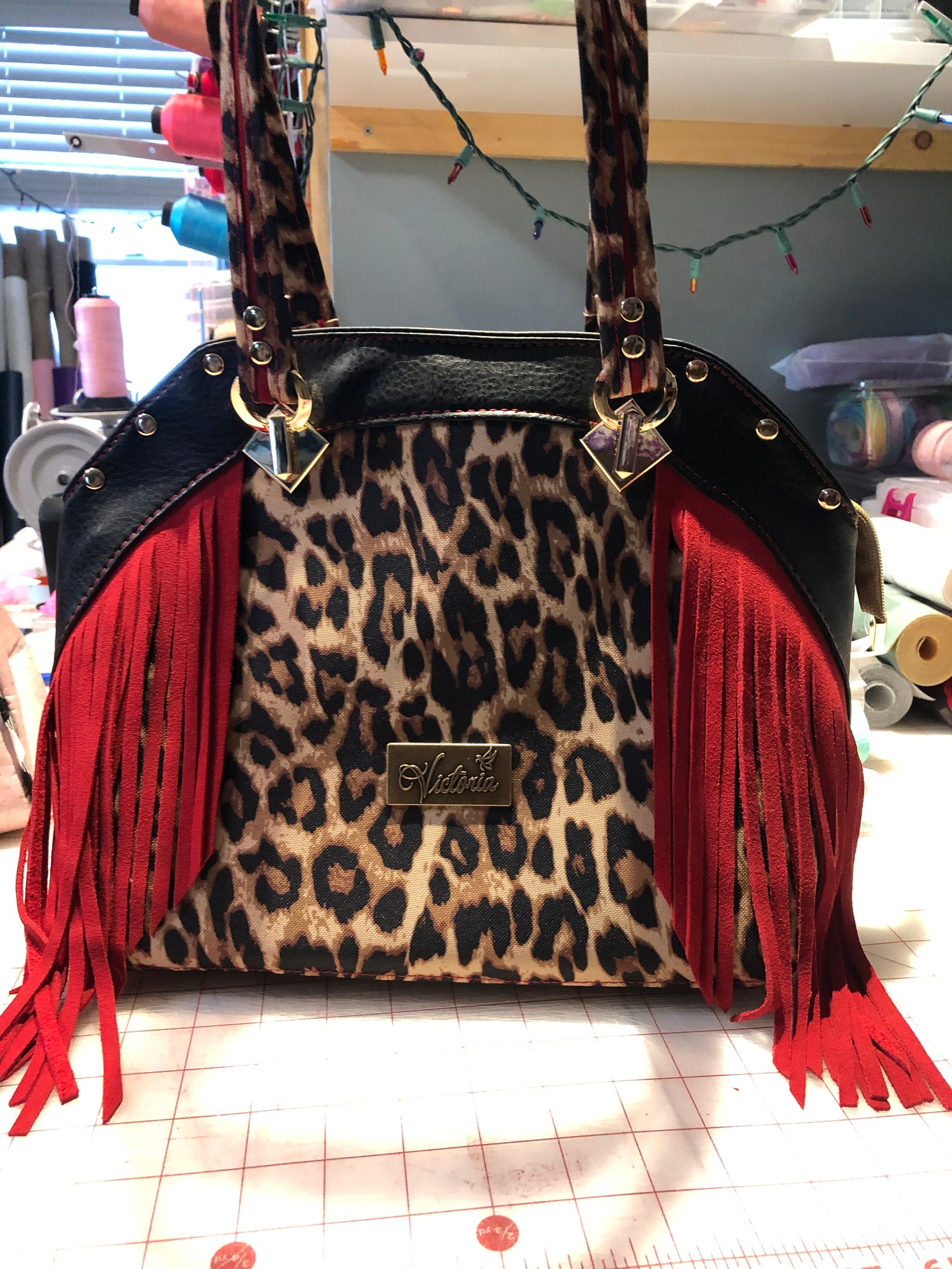 Red leather fring extends off the bag. Gold strap connectors and rivets.