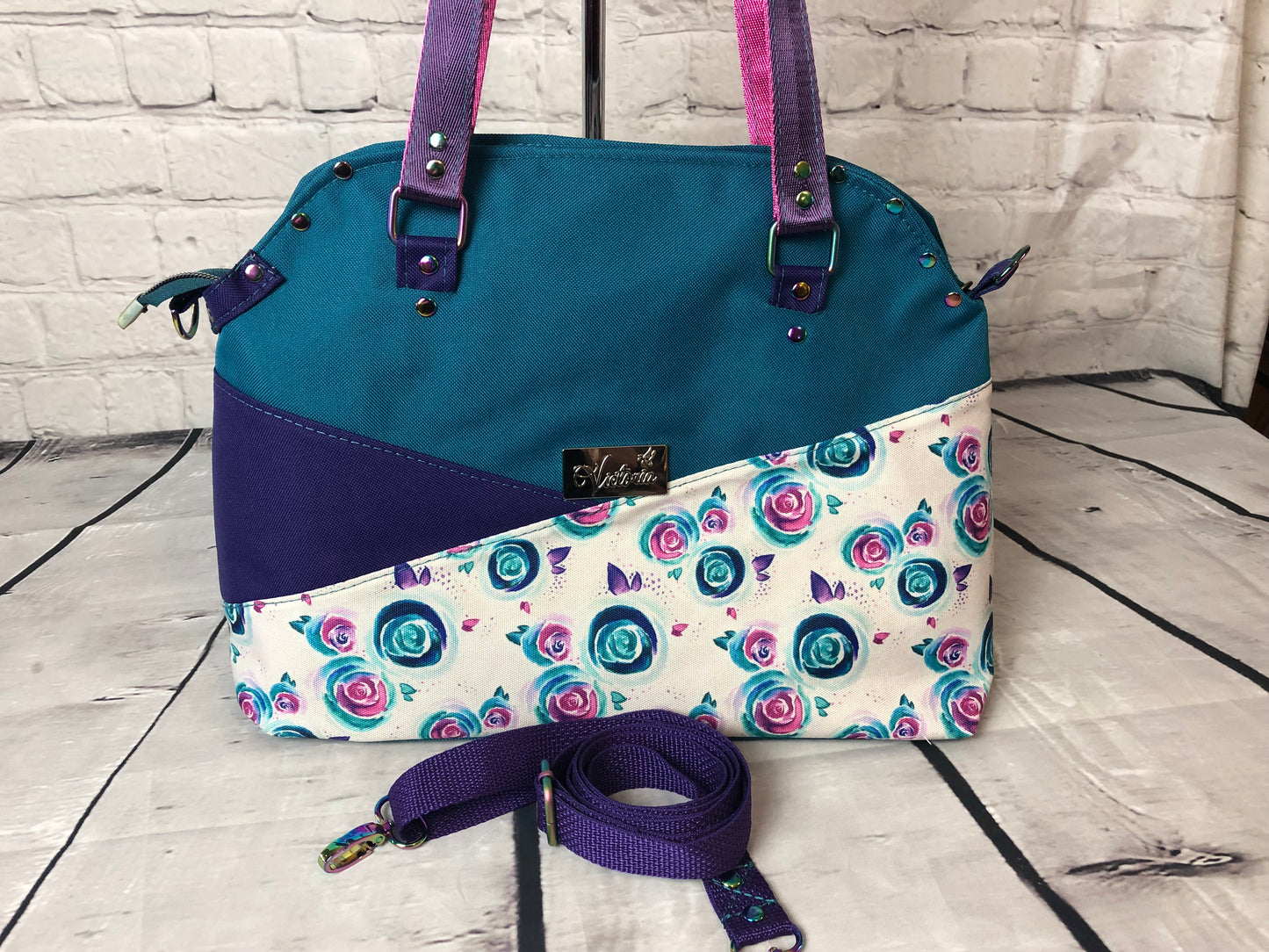 Josefa shoulder bag with crossbody strap. Sunglass loop on the exterior and pink/purple straps.