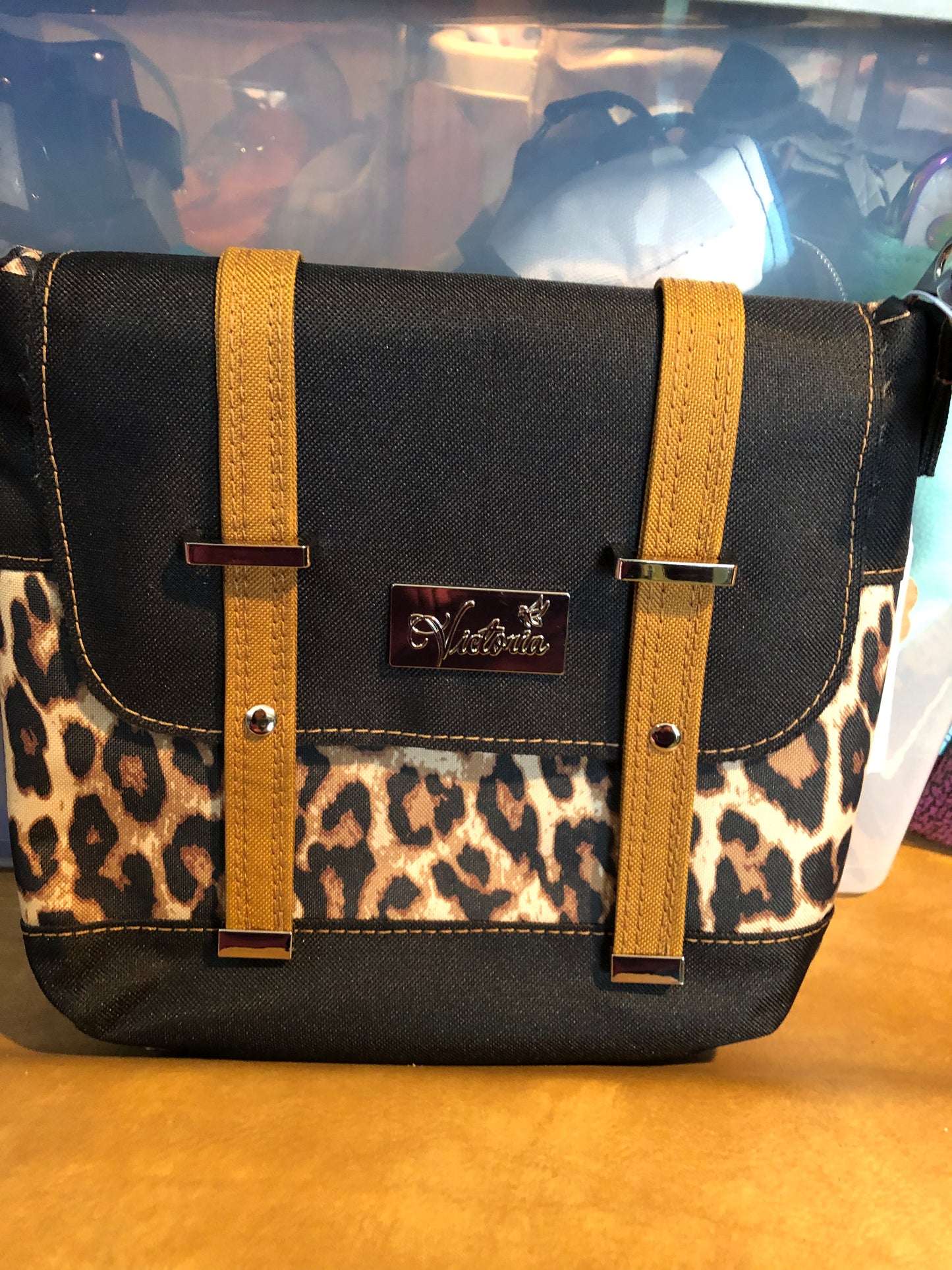 Small crossbody with adjustable crossbody strap. Red waterproof canvas interior. Decorative buckle front, snap closure
