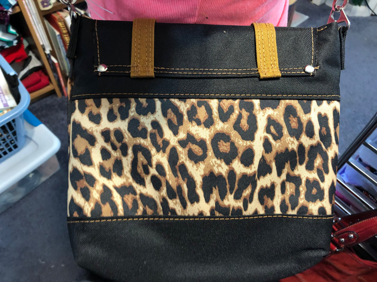 Small crossbody with adjustable crossbody strap. Red waterproof canvas interior. Decorative buckle front, snap closure