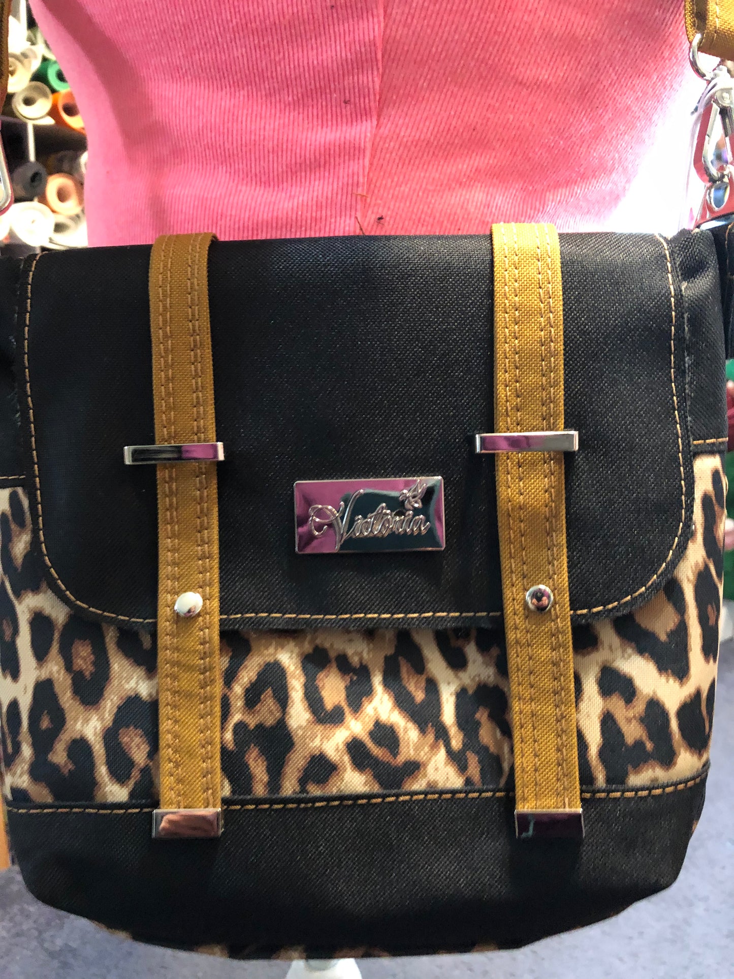 Small crossbody with adjustable crossbody strap. Red waterproof canvas interior. Decorative buckle front, snap closure