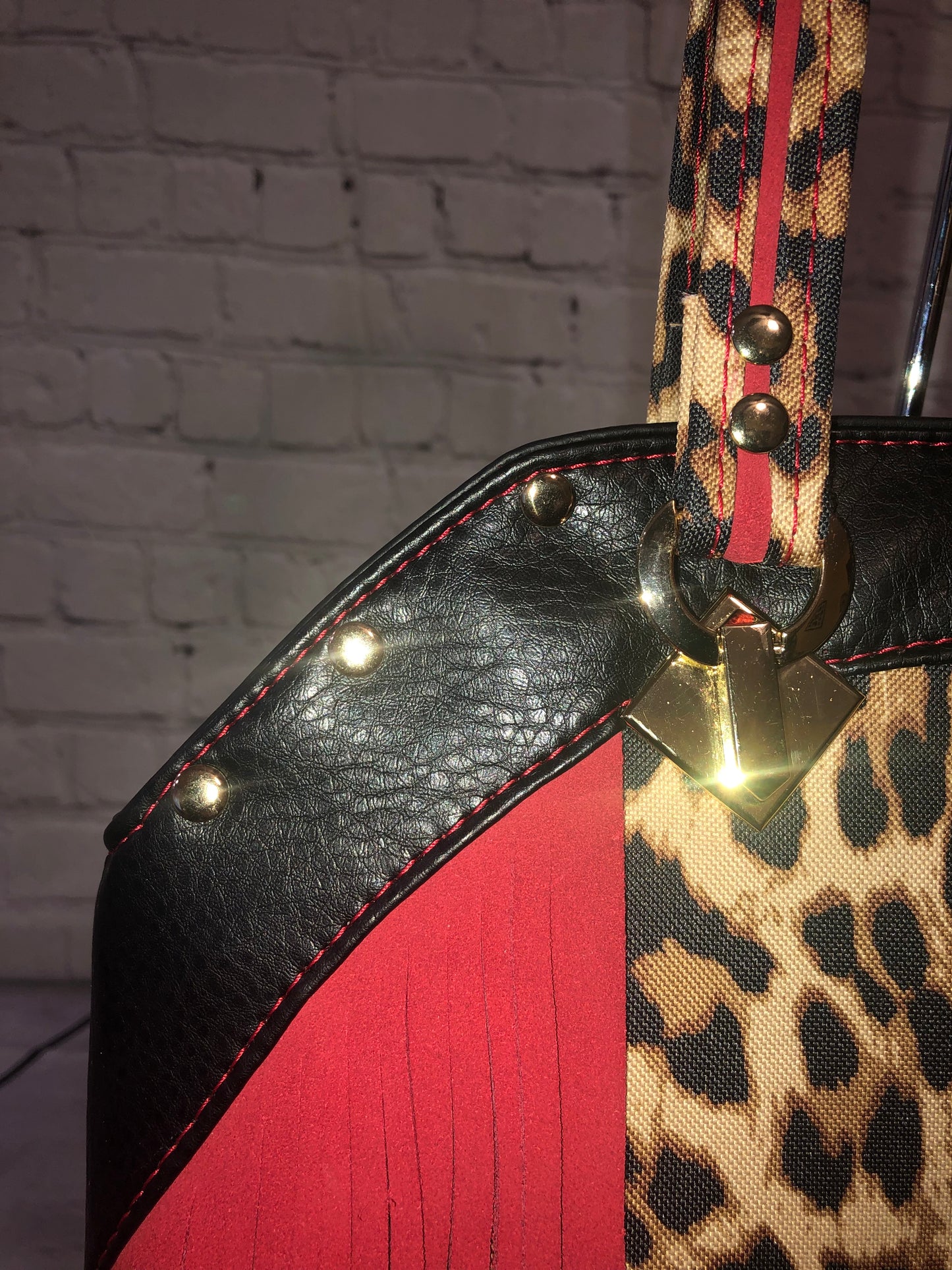 Close up of gold strap connectors. red leather trim & stitching