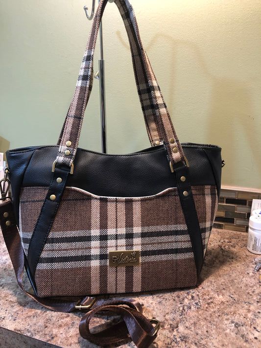 This classy brown and tan paid is a great everyday bag and even better a great bag for the fall season. Both vinyl and woven fabric come together on the sides to make a unique pattern.   There is an adjustable, detachable crossbody strap.  Top handles for crook of the arm or shoulder.