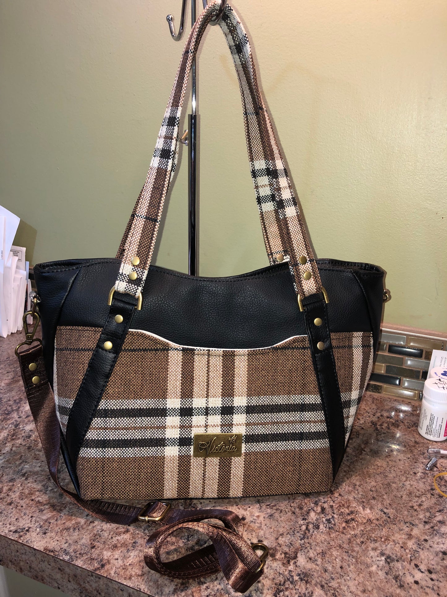 This classy brown and tan paid is a great everyday bag and even better a great bag for the fall season. Both vinyl and woven fabric come together on the sides to make a unique pattern.   There is an adjustable, detachable crossbody strap.  Top handles for crook of the arm or shoulder.