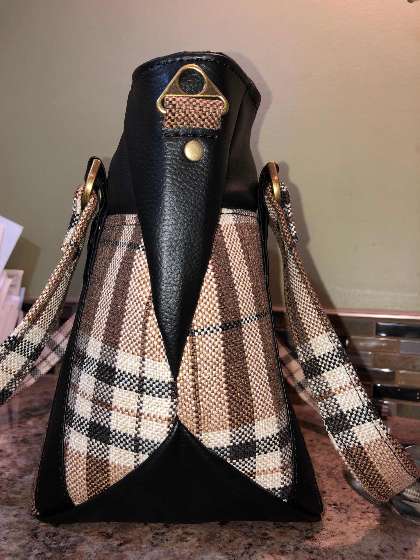 This classy brown and tan paid is a great everyday bag and even better a great bag for the fall season. Both vinyl and woven fabric come together on the sides to make a unique pattern.   There is an adjustable, detachable crossbody strap.  Top handles for crook of the arm or shoulder.