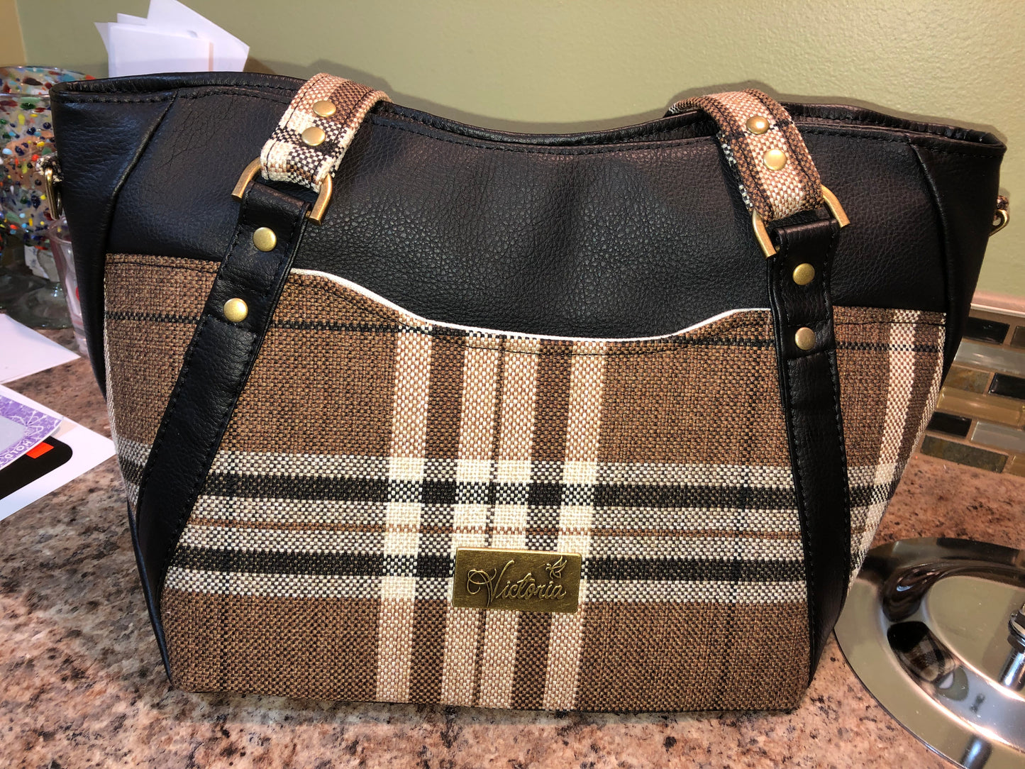 This classy brown and tan paid is a great everyday bag and even better a great bag for the fall season. Both vinyl and woven fabric come together on the sides to make a unique pattern.   There is an adjustable, detachable crossbody strap.  Top handles for crook of the arm or shoulder.