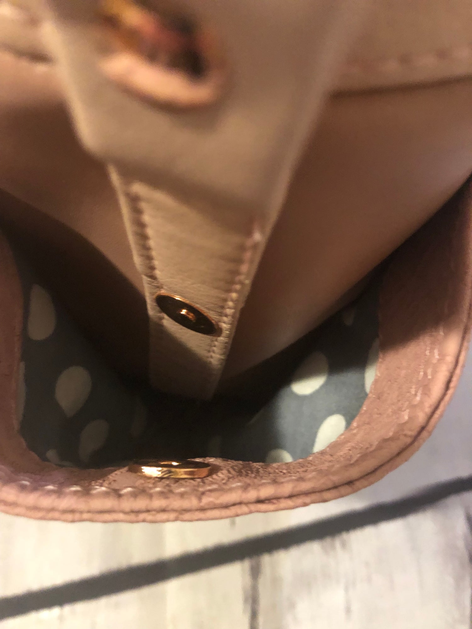 Looking down into Zoella exterior side pocket. Rose gold magnetic snap holds pocket shut.